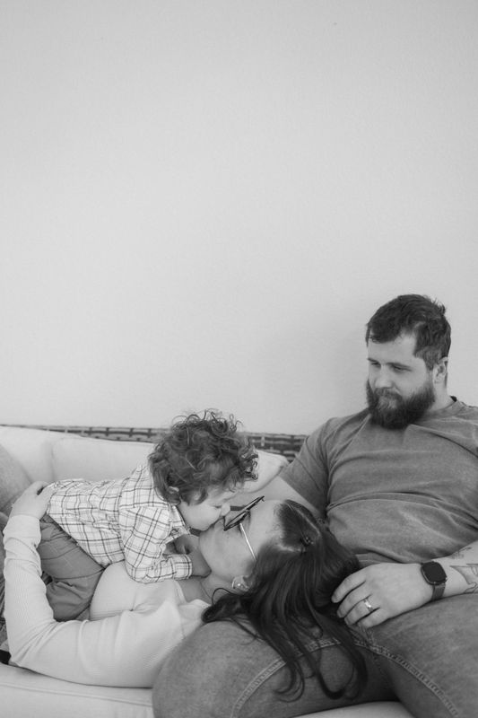 Black and white photo of a father and his toddler sitting close together on a couch