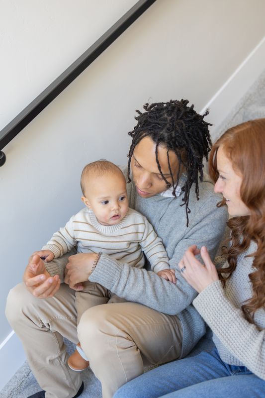 Close view of parents on a staircase with their baby reaching toward the camera