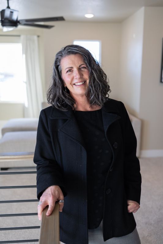 Close portrait of realtor Nicole Strom smiling, resting a hand on a stair rail